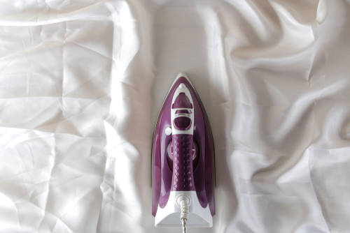 Lilac,Iron,On,A,Piece,Of,White,Crumpled,Fabric.,Ironing