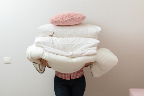 Woman,Holding,A,Pile,Of,Bedding,For,Sleeping