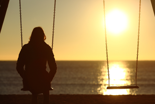 Lonely,Woman,Watching,Sunset,Alone,In,Winter,On,The,Beach