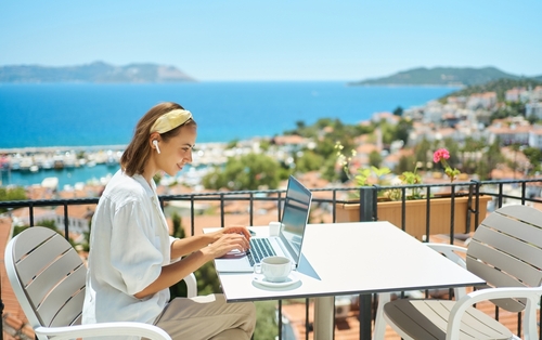 Young,Woman,Using,Laptop,Computer,At,Cafe,Balcony,Of,Resort
