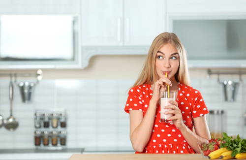 Young,Woman,With,Glass,Of,Delicious,Milk,Shake,In,Kitchen